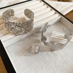 Textured silver flower open bangle and butterfly jewelry set on a white linen box
