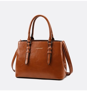 Macro detail of brown polished faux leather tote bag showing handle and hardware