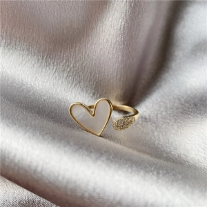 Detail of gold open ring with white heart inlay and crystal teardrop on silk fabric