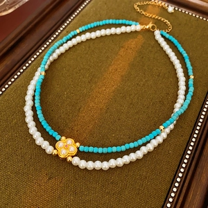 Dettaglio collana a due strati con perle e ciondolo a quadrifoglio dorato chic