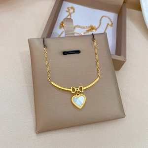 Golden titanium steel necklace with bow knot and white heart pendant on display stand