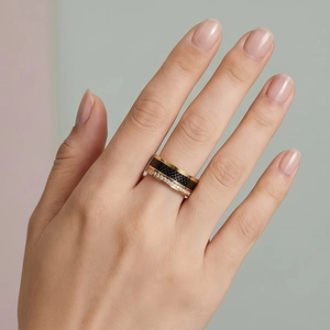 Close-up of a wide gold stainless steel ring featuring black inlay and micro-pave crystals