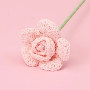 Close-up of a hand-knitted pink rose flower made from soft yarn for home decoration