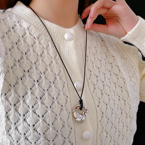 Close-up of geometric irregular silver pendant with adjustable black cord on model
