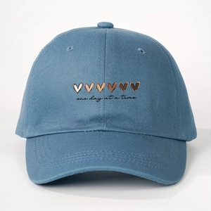Detail of blue cotton baseball cap with gradient hearts and one day at a time text
