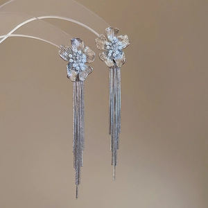 Detailed macro view of silver flower earrings with long tassels and pearl accents
