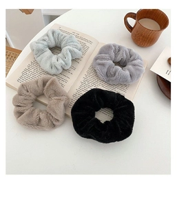 Close-up of four fluffy faux rabbit fur scrunchies on an open book for winter accessories