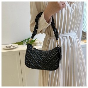 Detail of black quilted shoulder bag featuring V-shaped texture and gold hardware zipper
