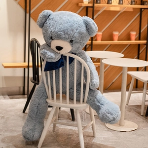 Soft blue teddy bear with dark blue bow sitting on a white chair in a cozy cafe setting