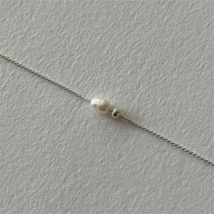 Macro detail of natural baroque pearl and silver bead on minimalist jewelry chain
