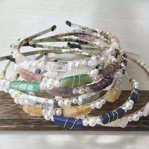 Close-up of handmade crystal crowns with pearls and raw stones on a dark wood base
