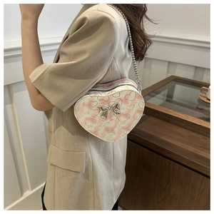 Pink and white gradient heart crossbody bag with silver bow shown on a model