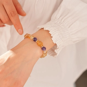 Close-up of a beaded amethyst and citrine bracelet on a wrist with golden spacers