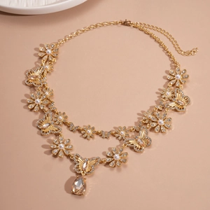 Macro shot of gold double-layer necklace with butterfly motifs and champagne teardrop crystal