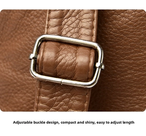 Close-up of brown textured leather strap with adjustable silver metal buckle on backpack