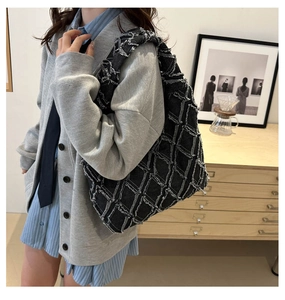 Detail of grey patchwork denim tote bag with textured frayed edges on shoulder