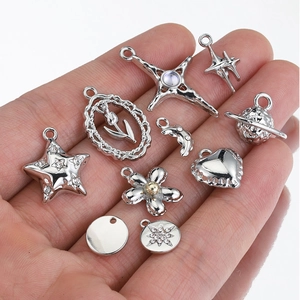 Silver Y2K charms set with star, heart, and cross shapes held in palm for size reference