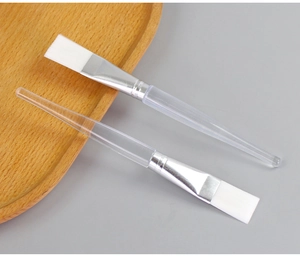 Detail of two facial mask brushes with clear crystal handles and white nylon bristles