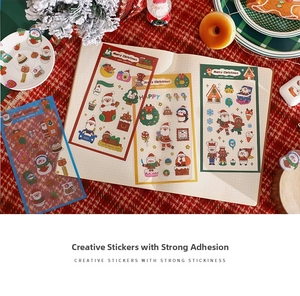 Flat lay of Christmas cartoon PET stickers with Santa and reindeer on a grid notebook