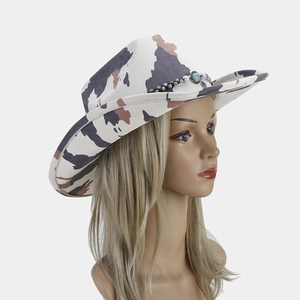 Detail of western cowboy hat with turquoise beads, feathers and cow print pattern