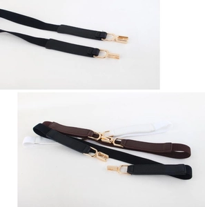 Close-up of elastic skinny belts with golden buckles in black, brown, and white colors