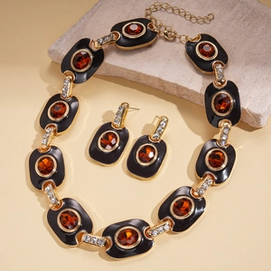 Detail of vintage gold necklace and earrings with amber stones and black enamel accents