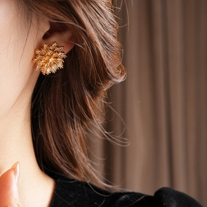Close-up of elegant gold snowflake earrings with sparkling zircons on a female model