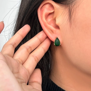 Elegant gold-plated drop earrings with pear-shaped emerald green zircon on a model