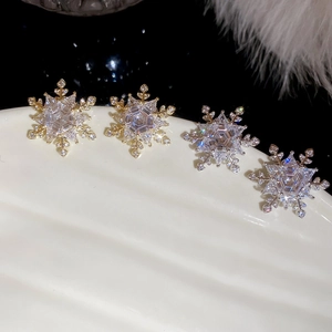 Macro shot of gold and silver snowflake stud earrings set with sparkling zircon crystals