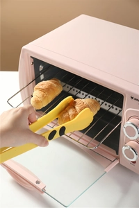 Yellow giraffe pattern silicone food tongs picking up a croissant from a pink oven