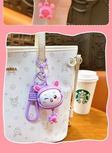 Simpatico portachiavi a forma di coniglio viola appeso a una borsa bianca a motivi.