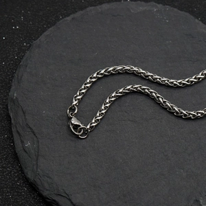 Vue macro d'une chaîne torsadée en acier inoxydable argenté avec fermoir mousqueton
