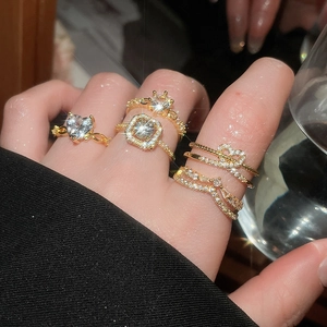 Close-up of layered gold zircon rings featuring heart and crown designs on hand