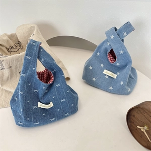 Detail of denim knot bags featuring butterfly and star patterns with red plaid lining