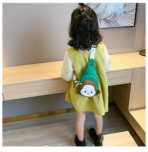 Girl wearing a green monkey cartoon chest bag with adjustable strap in home setting