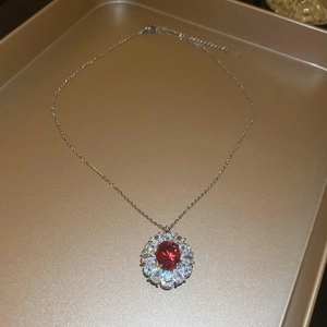 Dettaglio della collana vintage con pietra rossa ovale e zirconi su vassoio dorato