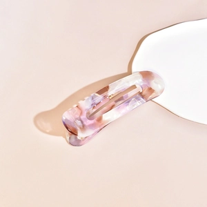 Detail of large acetate hair claw clip with purple and pink marble texture on ceramic plate