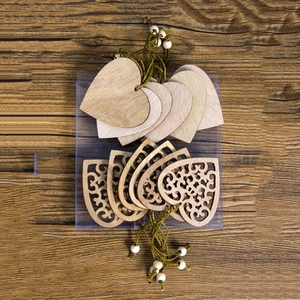 Set of rustic wooden heart ornaments with hollow patterns and jute strings on dark wood