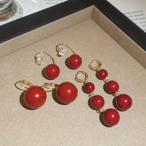 Macro detail of red resin beaded earrings and gold-plated hooks on jewelry tray