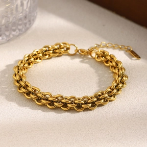 Detail of 18K gold plated lantern link chain bracelet with lobster clasp on textured surface