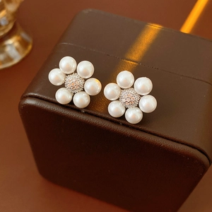 Macro shot of pearl flower earrings with zircon center on a brown jewelry box