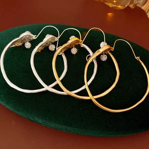 Close-up of gold and silver hoop earrings with diamond spheres on green velvet