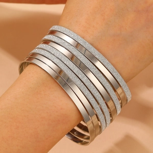 Macro detail of silver layered bracelets showing polished and frosted texture finishes
