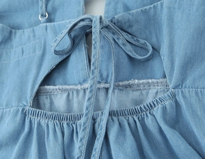 Détail d'une robe midi bleu clair avec nœud papillon au dos et découpe élégante