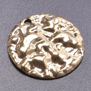 Macro shot of 18k gold plated round geometric pendant with hammered texture and top hole