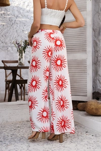 Détail du pantalon large blanc bohème orné d'un motif de soleil rouge dynamique