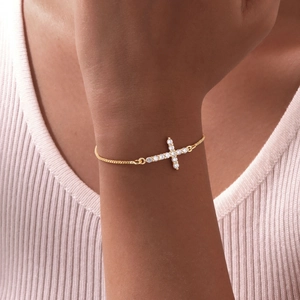 Close-up of gold adjustable box chain bracelet with sparkling cross pendant on wrist