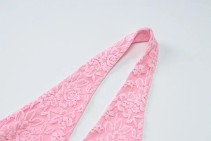 Gros plan sur la dentelle florale rose et les coutures délicates du haut dos nu ajusté