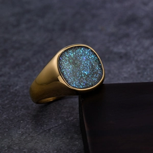 Macro view of men's gold signet ring featuring a teal crushed stone inlay on dark wood