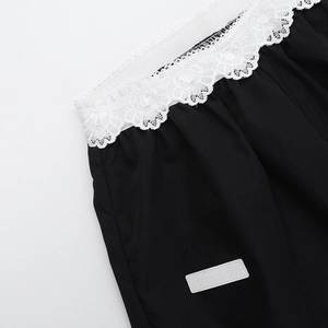 Vue détaillée de la bordure en dentelle blanche sur un pantalon d'été noir chic